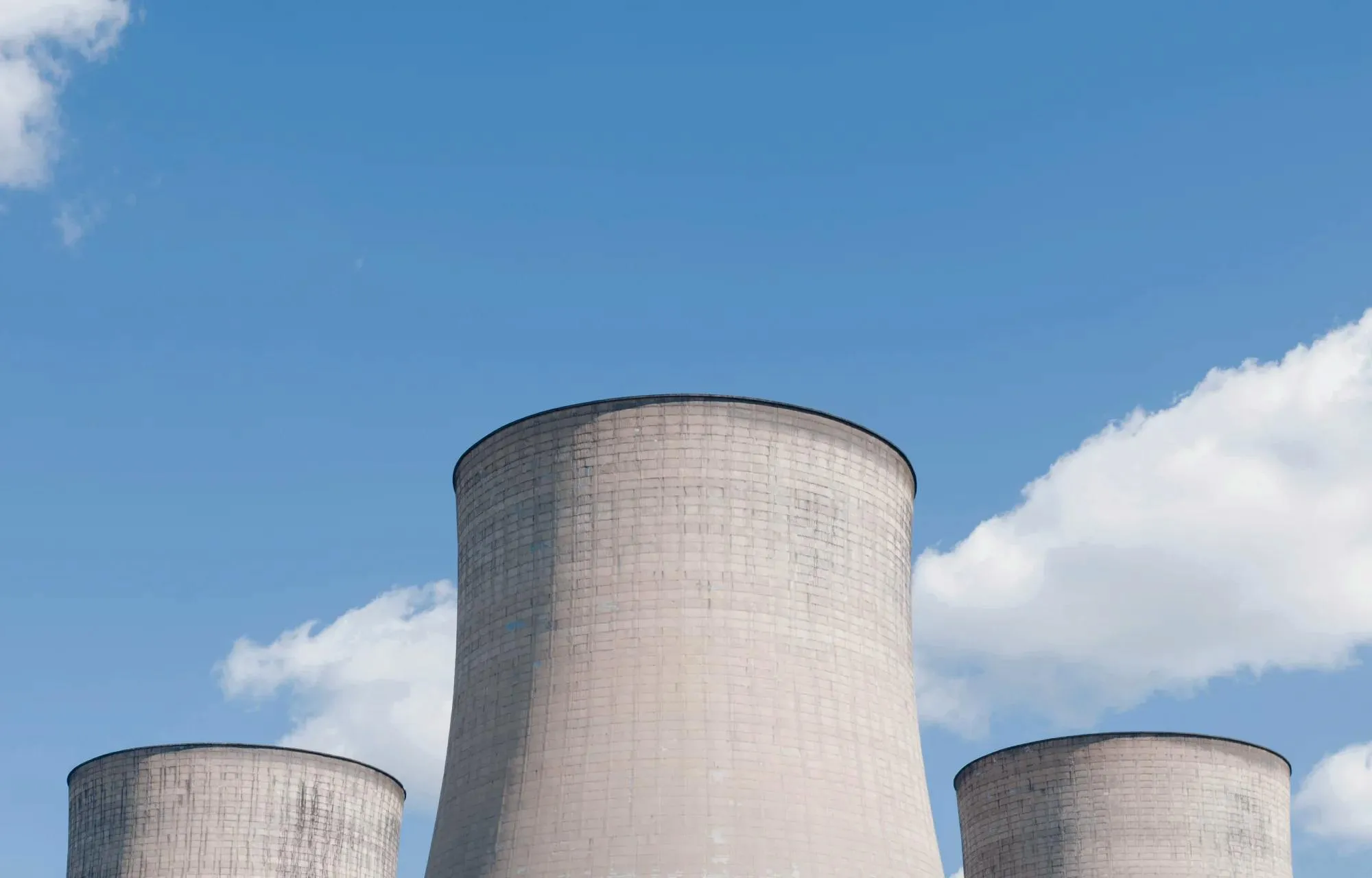 Three nuclear reactors side by side, with a blue sky in the background. 